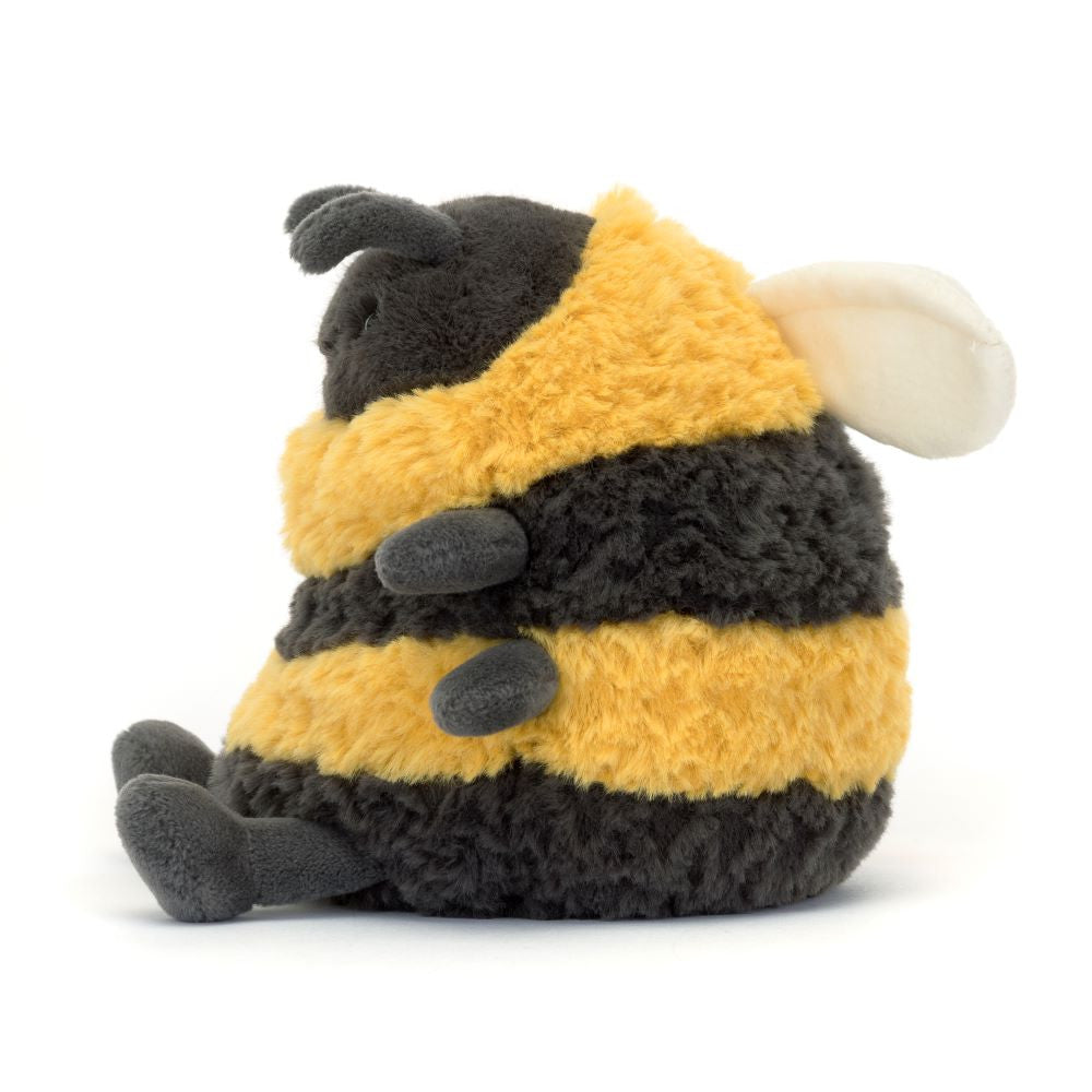 A side view of the Jellycat Albee Bee – Soft Plush Toy for Babies & Kids by Jellycat, shaped like a bumblebee with fuzzy black and yellow stripes, small grey legs, and white wings, sitting on a plain white background.
